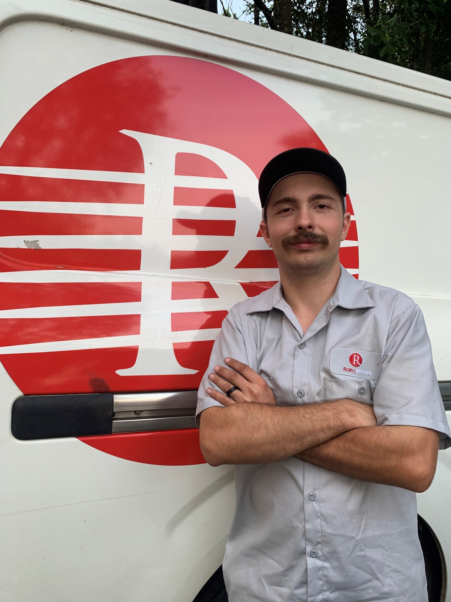 A Roby Services technician standing in front of a service van